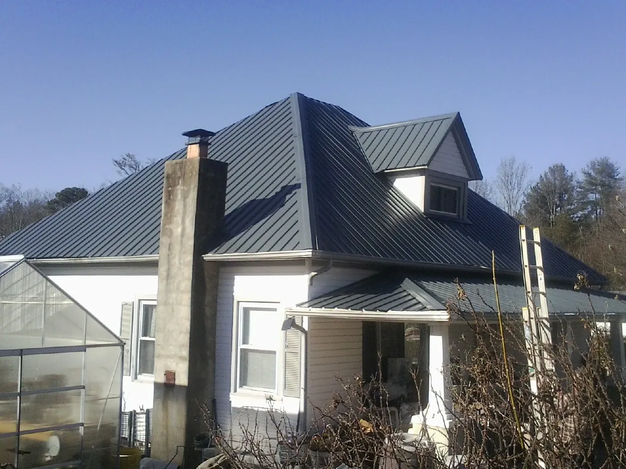 Dark blue standing seam metal roof on a white farmhouse with dormer — Slate & Tile Roof Repair by Roofing Brothers in Rochelle Park