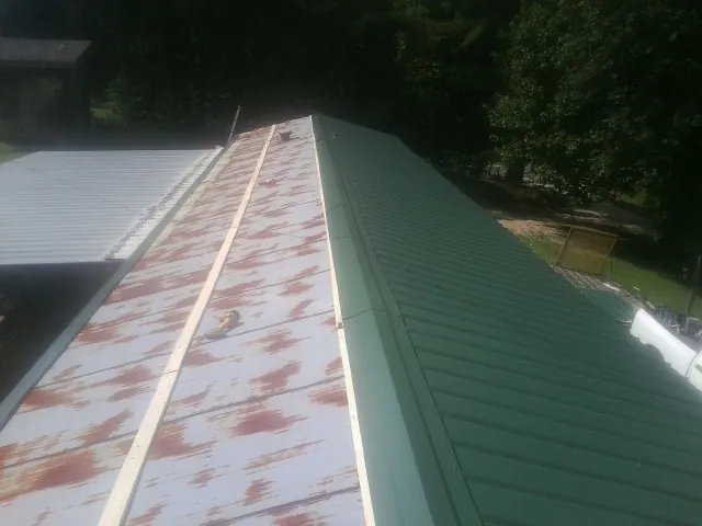 Old rusted panels beside newly installed green metal roofing — Wind Damage Roof Repair by Roofing Brothers in Rochelle Park