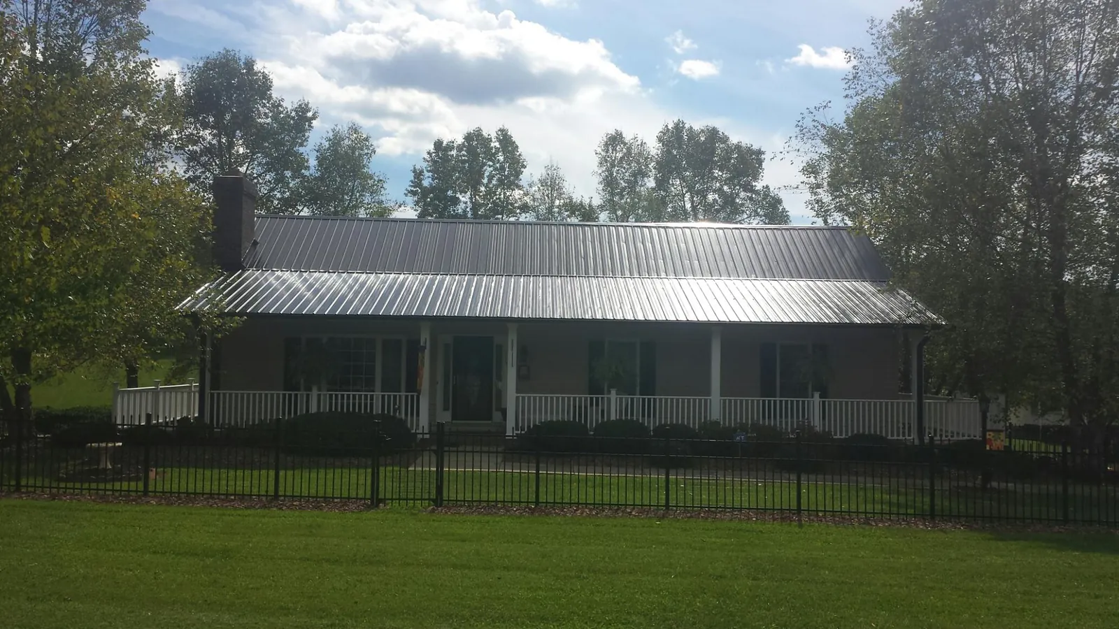 Gray metal roof on a brick ranch with a full width front porch — Gutter Guard Installation work by our crew in Rochelle Park