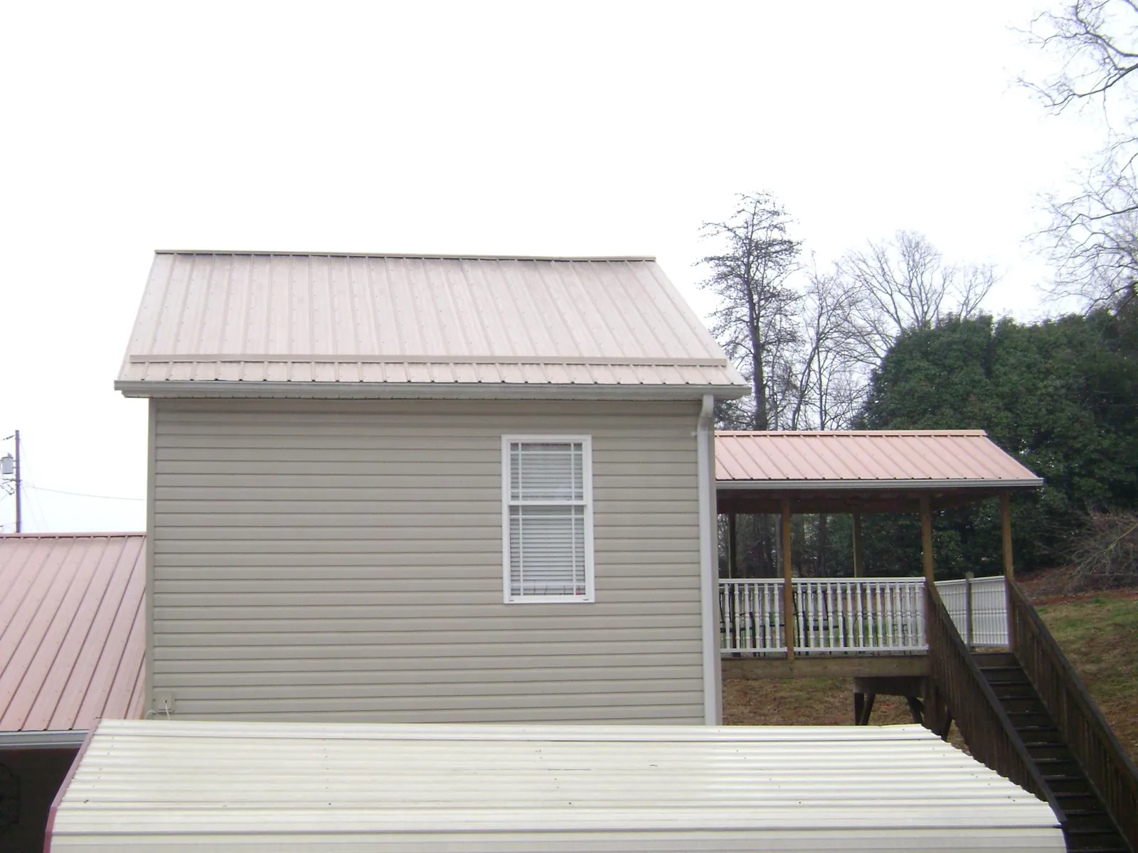 Tan metal roofs on a two story addition and attached porch, from a Roof Replacement job in Rochelle Park