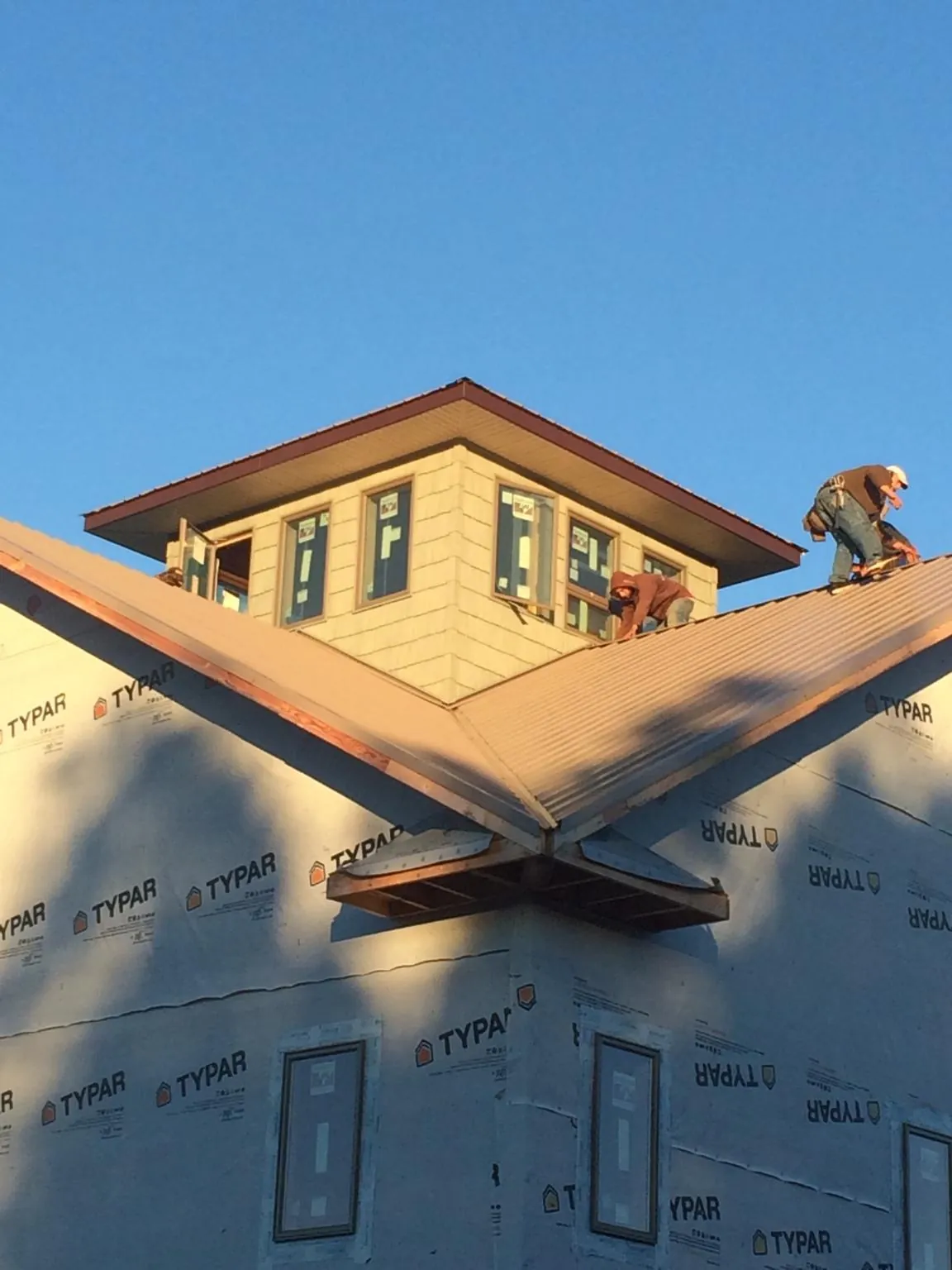 Roofers working around a rooftop cupola on a new metal roof at sunset — Roof Waterproofing in Rochelle Park by Roofing Brothers